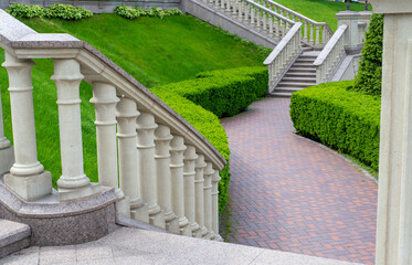 Stairways with stone railings balusters and iron lanterns, landscape design walking path for walking, green lawns and a variety of bushes