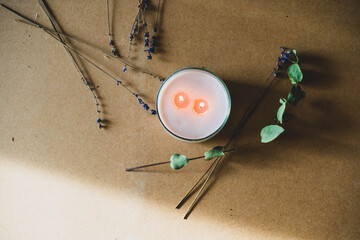 wooden wick candle. Handmade candle from paraffin and soy wax in glass with flowers and leaf on craft background. Let flay. Candle making. Top view.