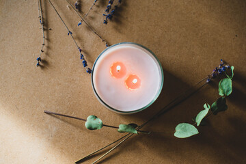 wooden wick candle. Handmade candle from paraffin and soy wax in glass with flowers and leaf on craft background. Let flay. Candle making. Top view.