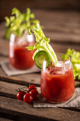Bloody or virgin mary cocktail served in a cup with celery sticks and cherry tomatoes