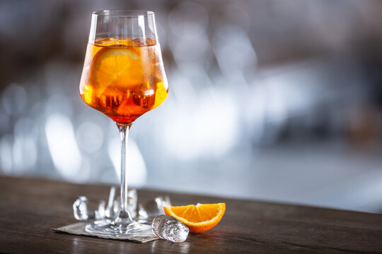 Typical summer sekt drink aperol spritz served in wine glass with aperol, prosecco, soda and a slice of orange