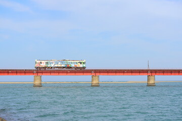 Fototapeta premium 赤い鉄を橋の上を走るカラフルな車両