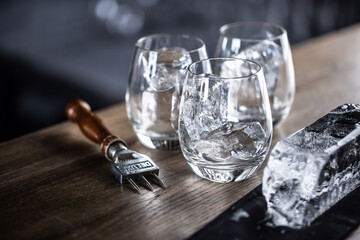Glasses cooled for cocktails with ice with a big ice cube and ice chopper aside