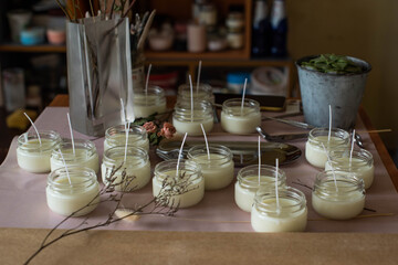Many soy wax candles together on store or workshop background. pottery store. Ecological and vegan business. Soya wax candle accessories. Handmade with love. Remote work, online shop, workplace