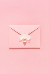 White Orchid flower on pink envelope. Congratulation card, Womens, Mothers Day, Valentines, birthday. Holiday background.