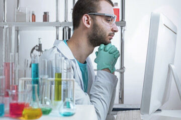 Chemistry laboratory assistant in protective glasses looks thoughtfully while working on the...