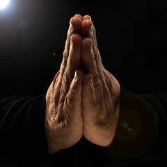 Close-up of hands woman in black clothes meditating, focus on arms in Namaste gesture