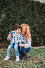 Mom playing with her little boy outdoors. Making soap bubbles with bubbles stick