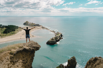 Man opening arms at the top of Castle Rock. Castle Point, New Zealand