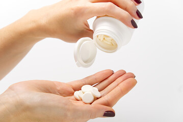 woman hand holding plastic jar with white pills, taking vitamins minerals drugs