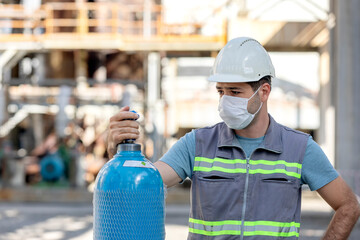 The worker is checking to the industrial compressed gas cylinder in the factory. A gas cylinder is...