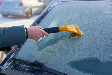 Cleaning the windshield of the car from the ice.