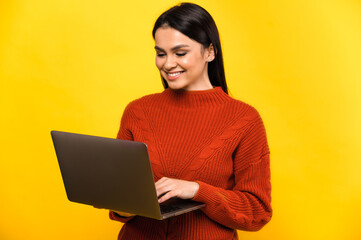 Attractive young caucasian smiling woman in casual sweater, stands on isolated yellow background...