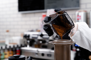 Making press coffee. Add coffe over natural background.