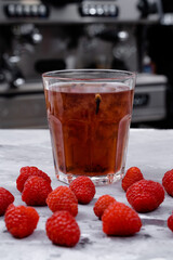Raspberry tea on white steel, against the background of a blurry bar and its interior.