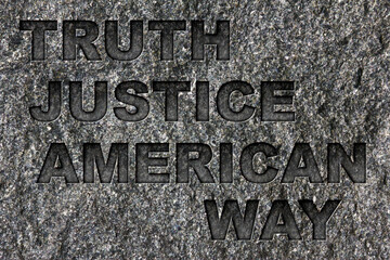 Truth Justice American Way etched in bold, dark gray text on black granite.