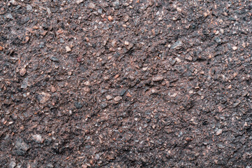 Rough surface old wall, fine granite stone mixed with biton mortar, textured background closeup, exposure to atmosphere, outdoors.