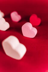 A little pink heart of sponge with with another hearts of sponge situated together on a red background. San Valentine's day backgrounds concept