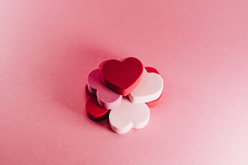 Top view of a pile of little hearts of sponges on a pink background. There are some heart of red, white and pink color. San Valentine's day backgrounds concept