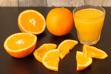Glass of fresh orange juice with fresh fruits on dark table