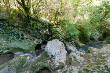 narrow mountain turquoise river among the stones with blurry background, used as a background or texture, soft focus