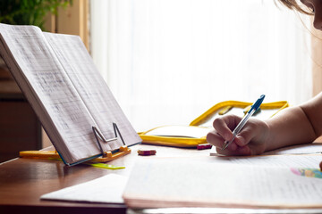 Child's hand writes in a notebook while doing homework, close-up