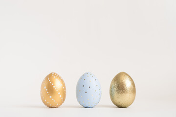 Three Easter golden decorated eggs on white background. Minimal easter concept. Happy Easter card with copy space for text. Top view, flatlay.
