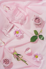 Obraz na płótnie Canvas Pink rose flowers in water with silk fabric and champagne glass. Valentines or woman's day background design. Minimal flat lay nature.