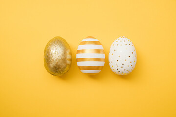 Easter golden decorated eggs on yellow background. Minimal easter concept. Happy Easter card with copy space for text. Top view, flatlay