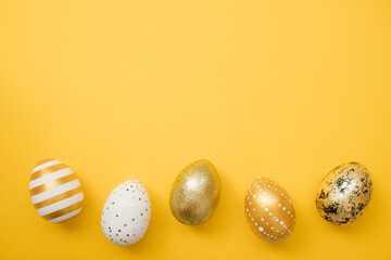 Easter golden decorated eggs on yellow background. Minimal easter concept. Happy Easter card with copy space for text. Top view, flatlay
