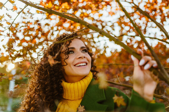 cute smile bared a number of white teeth on the face of a girl enthusiastically looking at the crimson leaves of the park trees. High quality photo