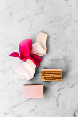 Rosen cake and pink petals decoration on the white marble background.