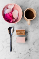 Cup of coffee with a spoon and a rose pink cake