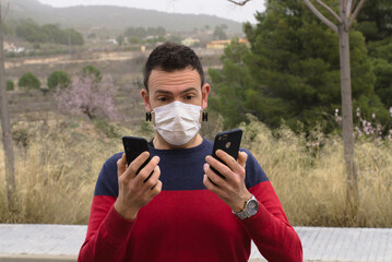 Shocked young man using two smartphones watching screen. Concept: internet addiction.