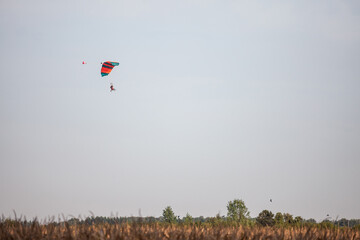 orange and Green parachute, made for two persons, a beginner and an instructor, falling fro the sky...