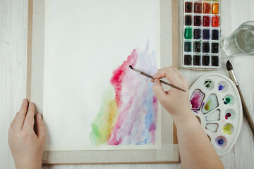 Hands of artist holding brush with watercolor painting