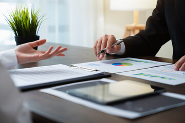 Businessman holding pen and financial document graph on the table with brainstorming in planning work.