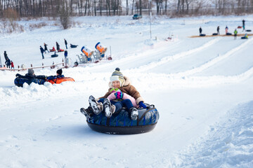 a boy and a girl ride a tubing downhill