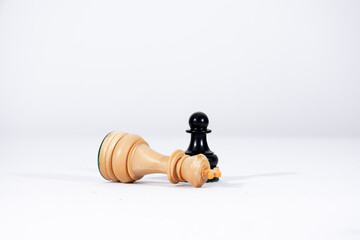 Strategy concept, black chess pawn and fallen white king with white background.