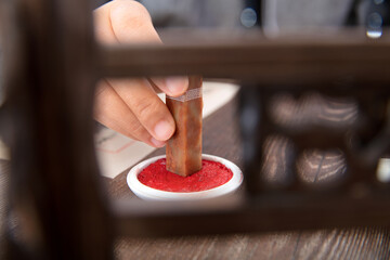 The artist holds a seal in his hand and stains it with red ink