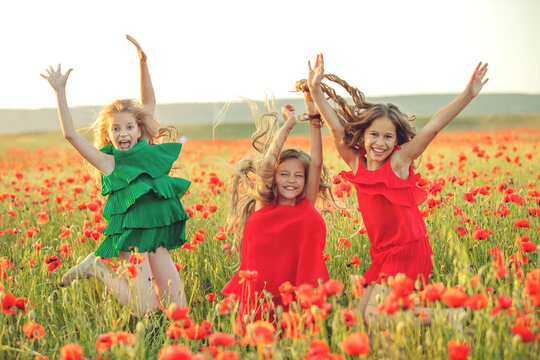 Group of happy children playing outdoors. Children have fun in the spring park. Girls run in the field with poppies. High quality photo.