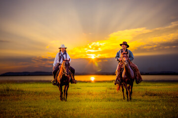 cowboys horseback riding at sunset time with sunlight ray sky background