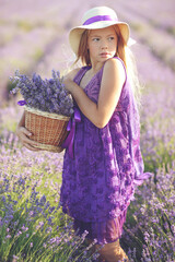 Photo of happy young girl in dress holding bouquet of flowers while walking in lavender field in summer. High quality photo.
