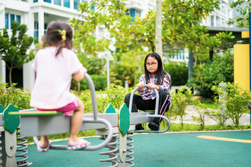 Kids playing at the see-saw in the playground. Siblings play together.
