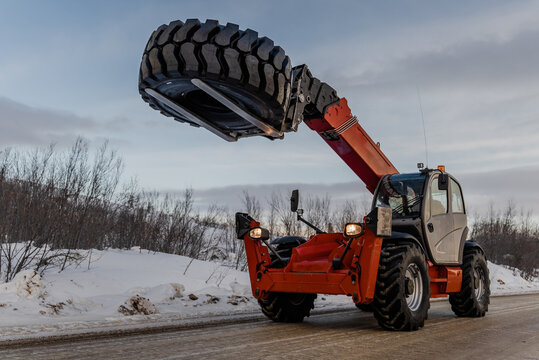 A telescopic forklift carries a tire.