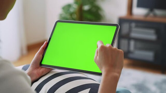 Close up of woman holding in hands a digital tablet with green screen for internet online, chromakey screen for advertising.