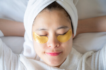 Young Asian woman sleeping while sticking under-eye masks for puffiness, dark circles, and wrinkles her under-eyes.