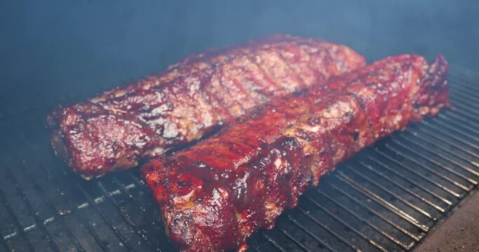 Brushing barbecue sauce on delicious smoked baby back pork ribs on a pellet grill smoker