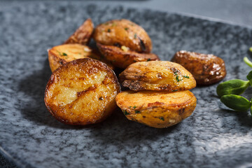 Roasted potato on dark restaurant plate. Vintage gray table. Gourmet food restaurant menu