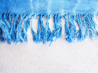 Close up indigo tie-dye fringe edge on beige cotton fabric texture.